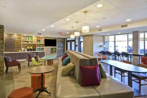 vestíbulo con sofá, mesas y sillas en Home2 Suites By Hilton Warner Robins, en Warner Robins