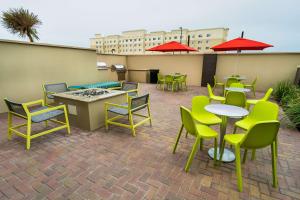a patio with tables and chairs and red umbrellas at Home2 Suites By Hilton San Antonio At The Rim, Tx in San Antonio