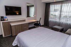 a hotel room with a bed and a desk and a television at Hampton Inn & Suites By Hilton Puebla in Puebla