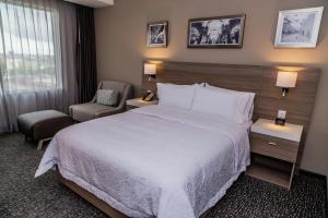 a hotel room with a large bed and a chair at Hampton Inn & Suites By Hilton Puebla in Puebla