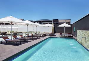 una piscina con sedie e ombrelloni in un edificio di Hilton Garden Inn Gaborone, Botswana a Gaborone