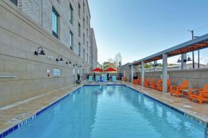 a swimming pool with orange chairs and a building at Home2 Suites Charleston West Ashley in Charleston
