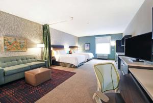 Home2 Suites By Hilton Beloit في بيلويت: غرفة فندقية بسرير وتلفزيون بشاشة مسطحة