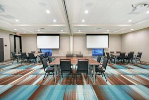 Home2 Suites By Hilton Beloit في بيلويت: قاعة اجتماعات مع طاولات وكراسي وشاشات