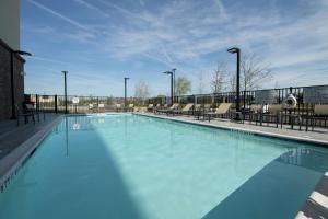 duży basen z niebieską wodą i krzesłami w obiekcie Hampton Inn & Suites Snellville Atlanta Ne w mieście Snellville