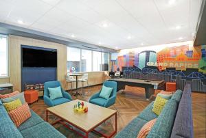Tru By Hilton Grand Rapids Airport في Kentwood: غرفة ألعاب مع طاولة بلياردو وكراسي زرقاء