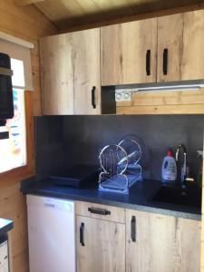 une cuisine avec des placards en bois et un comptoir noir dans l'établissement CHALET MARYVONNE, aux Vans