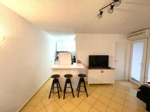a kitchen with two bar stools and a counter with a tv at Apartments Medunić in Ribarica