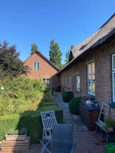 una casa de ladrillo con un patio con una silla blanca en Idylle unter Reet, gemütliche Ferienwohnug en Haseldorf