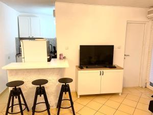 a kitchen with three stools in front of a television at Apartments Medunić in Ribarica
