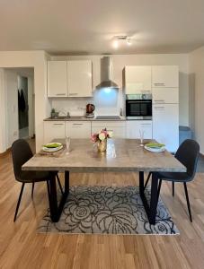 a kitchen with a table with two chairs and a kitchen with white cabinets at Confortable appart. en résidence (rez-de-chaussé) in Dudelange