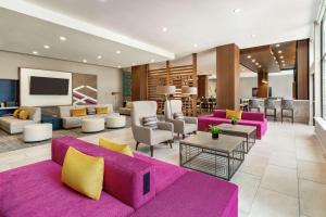 a living room with a purple couch and chairs at Hilton Garden Inn Seattle Airport in SeaTac