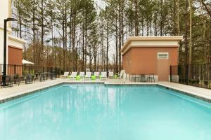 uma grande piscina azul com cadeiras e mesas em Hampton Inn And Suites By Hilton Johns Creek em Johns Creek