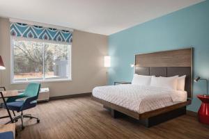 um quarto de hotel com uma cama e uma cadeira e uma janela em Tru By Hilton Greenville Woodruff Road, SC em Greenville