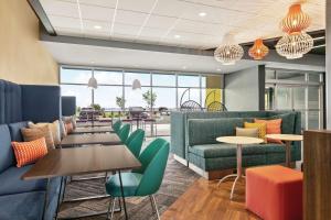 un restaurante con mesas, sillas y ventanas en Tru By Hilton Sebring FL, en Sebring