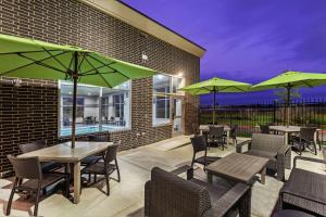 a patio with tables and chairs with green umbrellas at Hampton Inn Gardner in Gardner