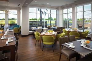 a restaurant with tables and chairs and windows at Hilton Garden Inn Sacramento Airport Natomas in Sacramento