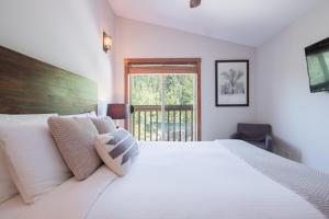 a bedroom with a large white bed and a window at Taluswood Bluffs by Outpost Whistler in Whistler
