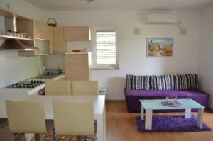 a kitchen and living room with a table and a purple couch at Apartments Soldo in Baška