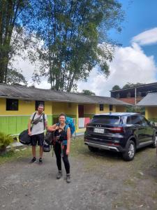 dos personas parados frente a una casa en Hostal Henrry's, en Mindo