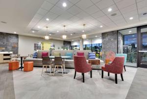 een lobby met een bank en tafels en stoelen bij Home2 Suites By Hilton Yakima Airport in Yakima