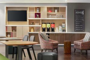 ein Restaurant mit 2 Tischen und Stühlen und einem TV in der Unterkunft Home2 Suites By Hilton Overland Park, Ks in Overland Park