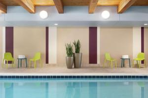 una piscina con sillas verdes y sillas junto a en Home2 Suites By Hilton Overland Park, Ks, en Overland Park