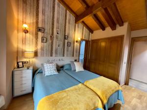 um quarto com uma cama azul e um tecto de madeira em La Llardana em Benasque