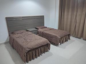 2 camas con mantas marrones en una habitación en رحاب السعاده rehab alsaadah apartment, en Salalah