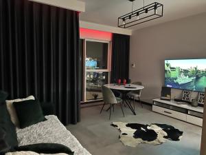 ein Wohnzimmer mit einem TV und einem Tisch sowie ein Esszimmer in der Unterkunft Towarowa - Milionowa 39 Check-in 24H in Posen