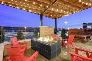 eine Terrasse mit roten Stühlen und einer Feuerstelle in der Unterkunft Embassy Suites Jonesboro - Arkansas State in Jonesboro