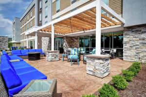 a patio with blue couches and chairs and a building at Home2 Suites By Hilton Georgetown in Georgetown