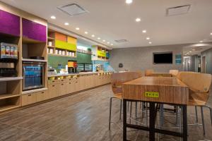 a restaurant with a table and chairs in a cafeteria at Home2 Suites By Hilton Loves Park Rockford in Loves Park