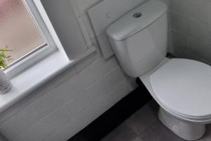 a white toilet in a bathroom with a window at Your Home away from Home. in Headingley