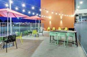 een patio met tafels en stoelen en roze parasols bij Home2 Suites By Hilton Foley in Foley