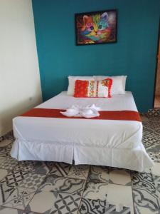 1 dormitorio con 1 cama con una pintura en la pared en El Rancho De Don Moncho Hostel 