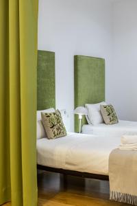 two beds in a room with green curtains at BNBHolder Apartamentos en Sol Confort 5 in Madrid