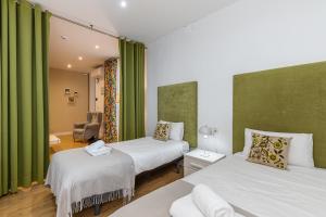 2 camas en una habitación con cortinas verdes en BNBHolder Apartamentos en Sol Confort 5 en Madrid
