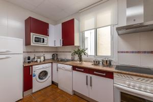 a kitchen with red cabinets and a washer and dryer at BNBHolder Apartamentos en Sol Confort 5 in Madrid