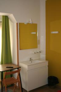 a bathroom with a sink and a mirror and a table at Hostal Juventus in Portbou
