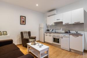 uma cozinha e sala de estar com um sofá e uma mesa em BNBHolder Apartamentos en Sol Confort 3 em Madri