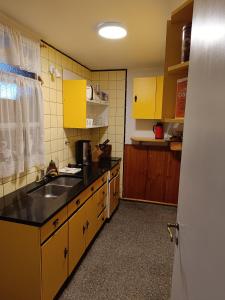 una cocina con armarios amarillos y fregadero en Departamento Centro en Bahía Blanca