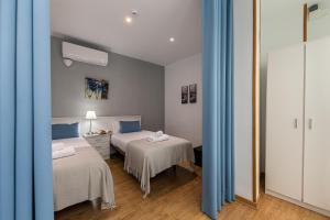 sypialnia z 2 łóżkami i niebieskimi zasłonami w obiekcie Waou Apartamentos en Sol Confort 3 w Madrycie +6 zdjęć