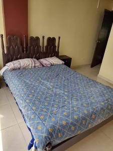 uma cama com um edredão azul num quarto em Ideal para descansar em Ambato