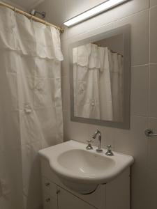 Baño blanco con lavabo y espejo en Departamento Centro en Bahía Blanca