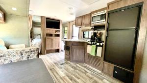 an rv kitchen with a black refrigerator and wooden floors at Rainier RV half a mile away from Mt Rainier in Ashford