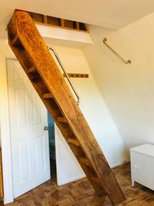 escalera de madera en una habitación con puerta blanca en Cabaña para Dos - Tinaja Privada e Hidromasaje - Mirador Llaima, en Curacautín