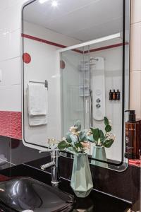 a bathroom sink with a mirror and two vases with flowers at BNBHolder Apartamentos en Sol Deluxe 3 in Madrid