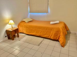 Departamento en Mendoza Capital في ميندوزا: سرير صغير في غرفة مع مصباح على طاولة
