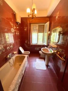 La salle de bains est pourvue de 2 toilettes, d'une baignoire et d'un lavabo. dans l'établissement Spacious house in the green heart of Italy, à Colpetrazzo